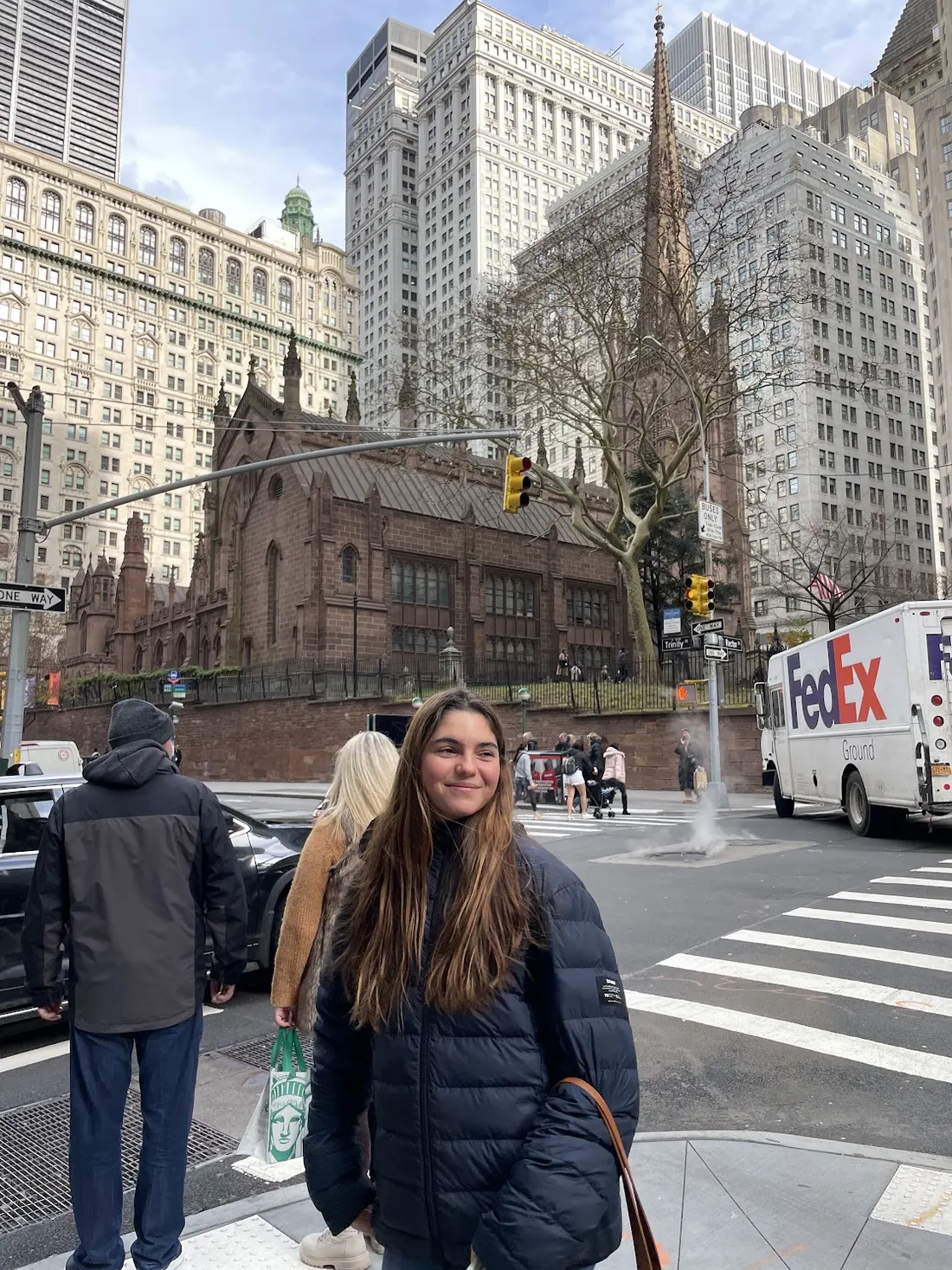 Raquel on a New York street corner with Trinity Church behind