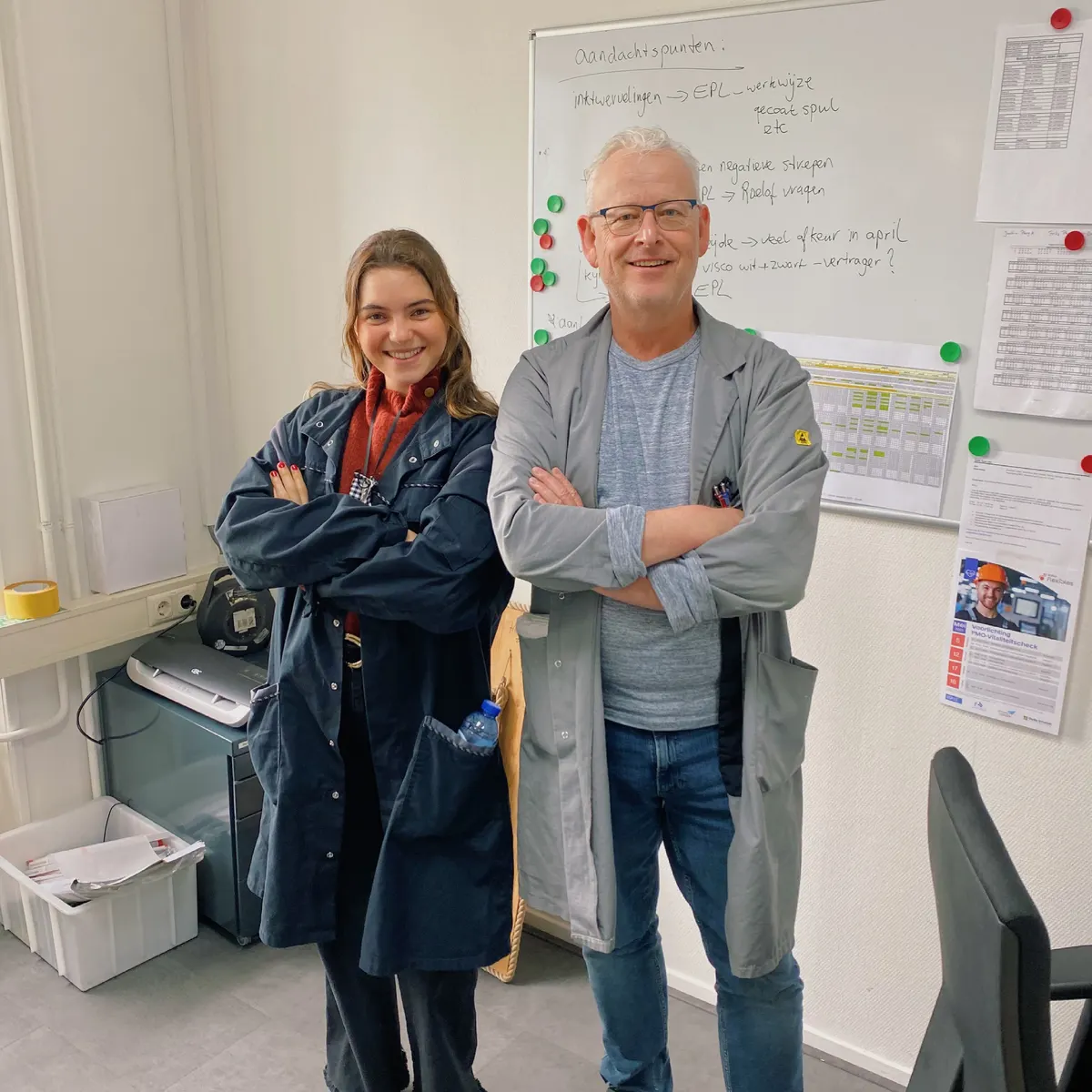 Raquel and a colleague in work coats, arms crossed, in an office at the plant