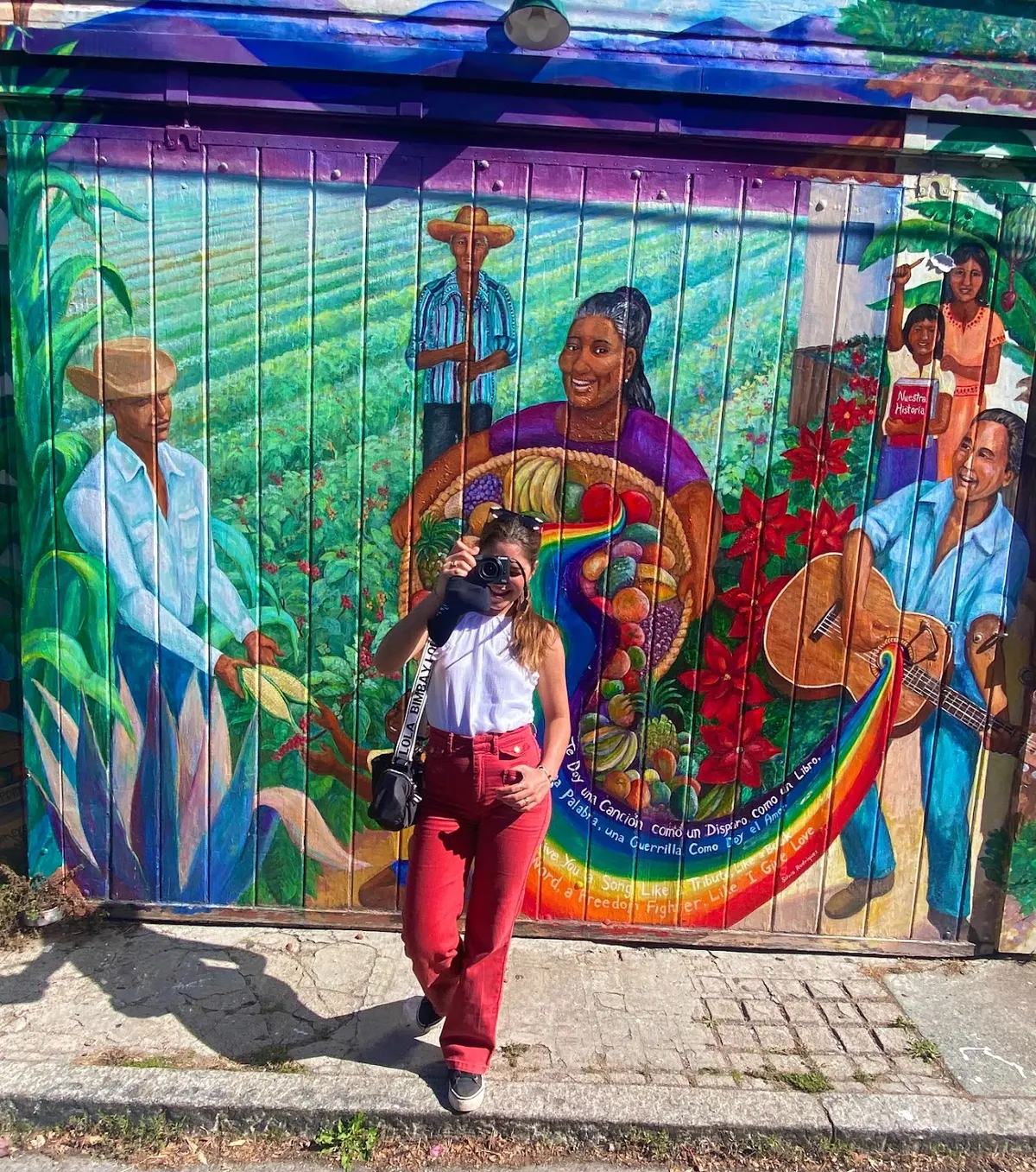 Raquel taking a photo in front of a colourful mural in San Francisco